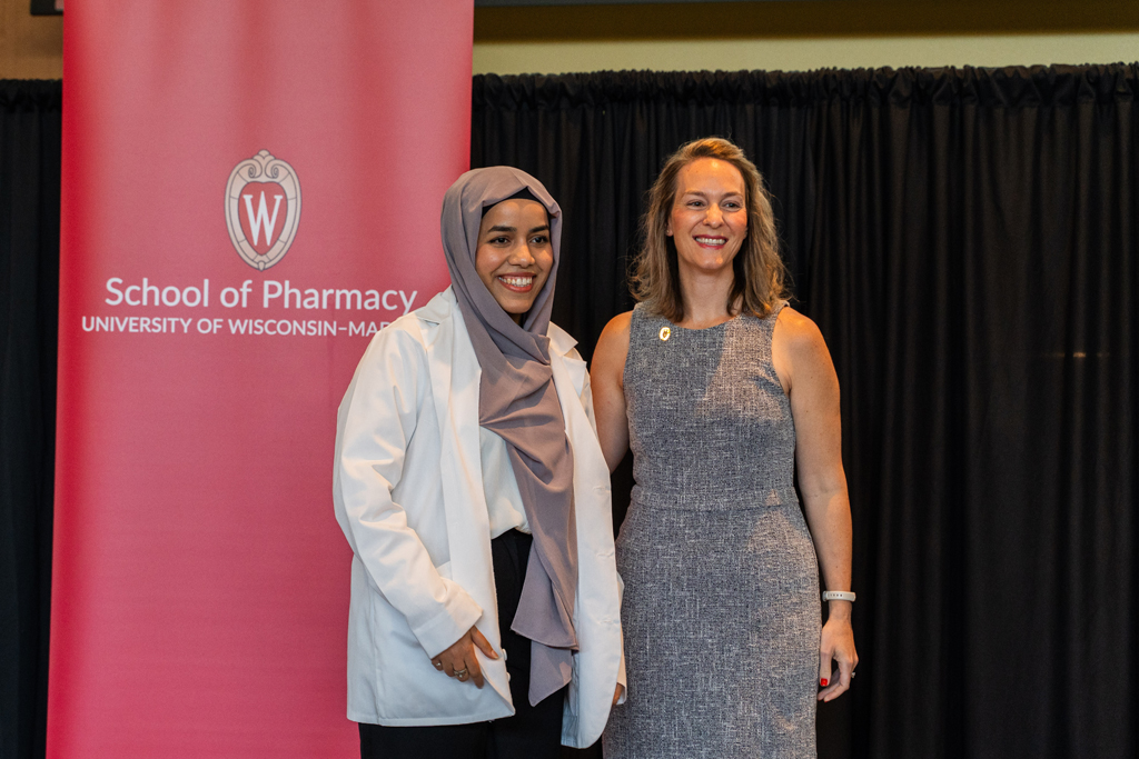 Photo by Paulius Musteikis A student poses with Kate Rotzenberg in front of a red School of Pharmacy banner