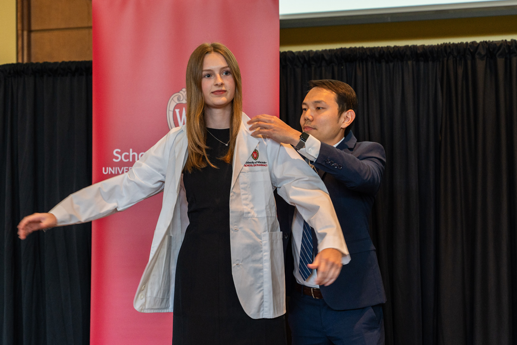 Photo by Paulius Musteikis A student receives her white coat from Sean Lim