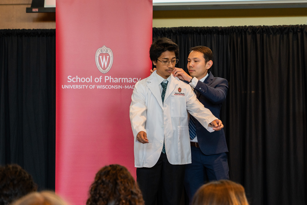 Photo by Paulius Musteikis A student receives his white coat from Sean Lim