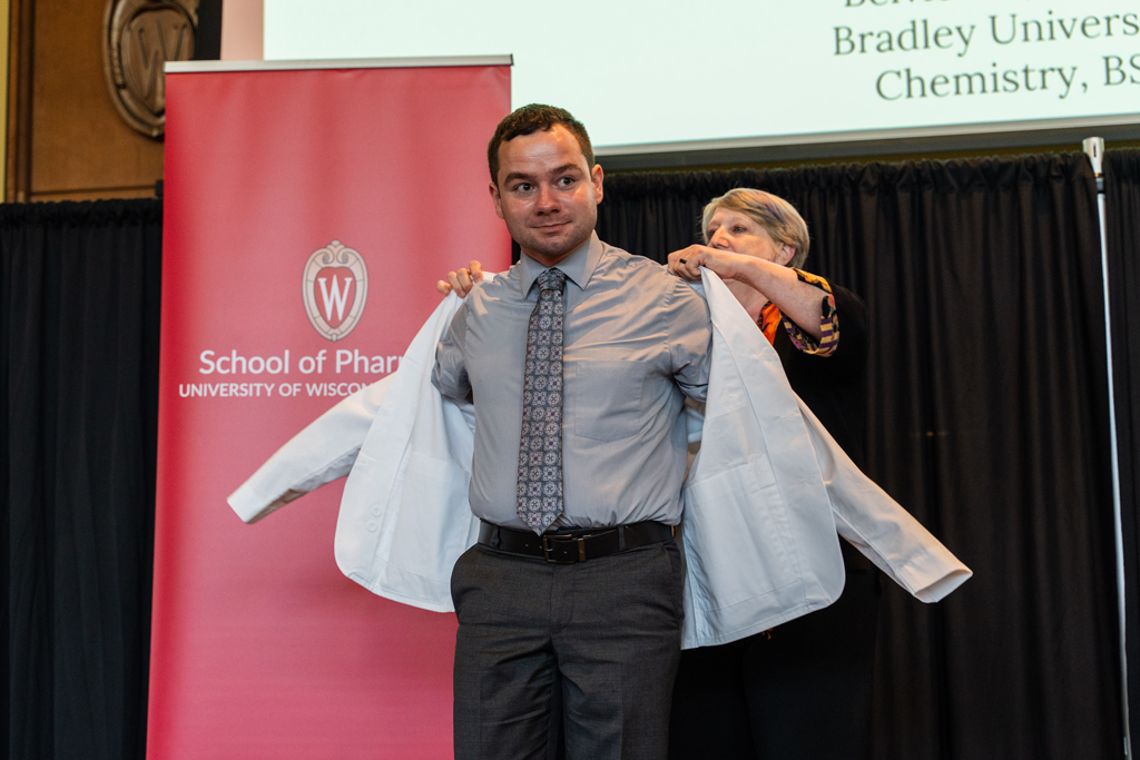 Photo by Paulius Musteikis A student receives his white coat from Karen Kopacek