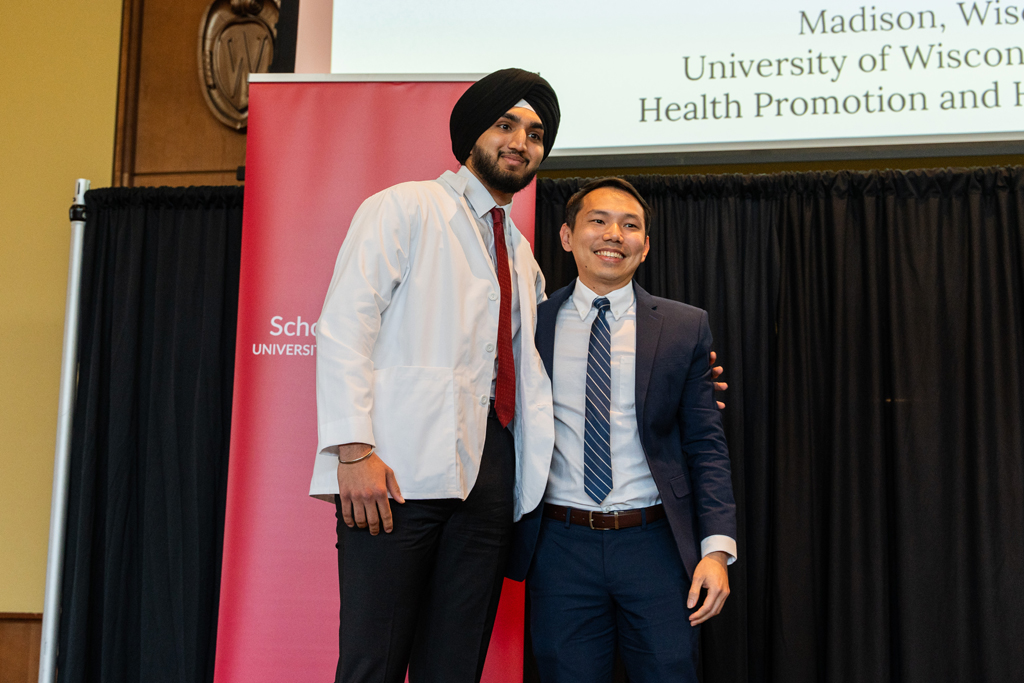 Photo by Paulius Musteikis A student poses with Sean Lim in front of a red School of Pharmacy banner