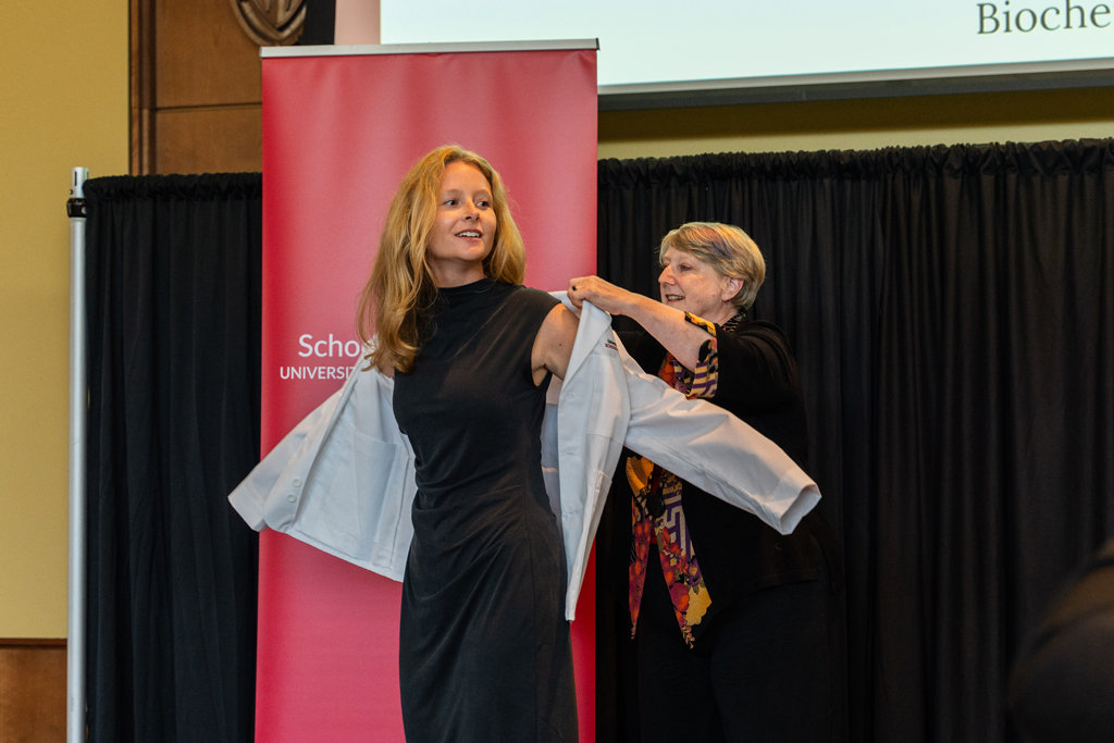 Photo by Paulius Musteikis A student receives her white coat from Karen Kopacek