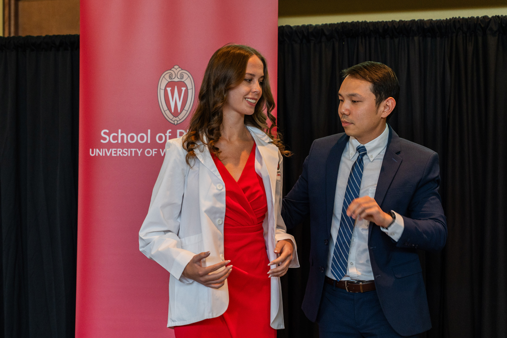 Photo by Paulius Musteikis A student receives her white coat from Sean Lim