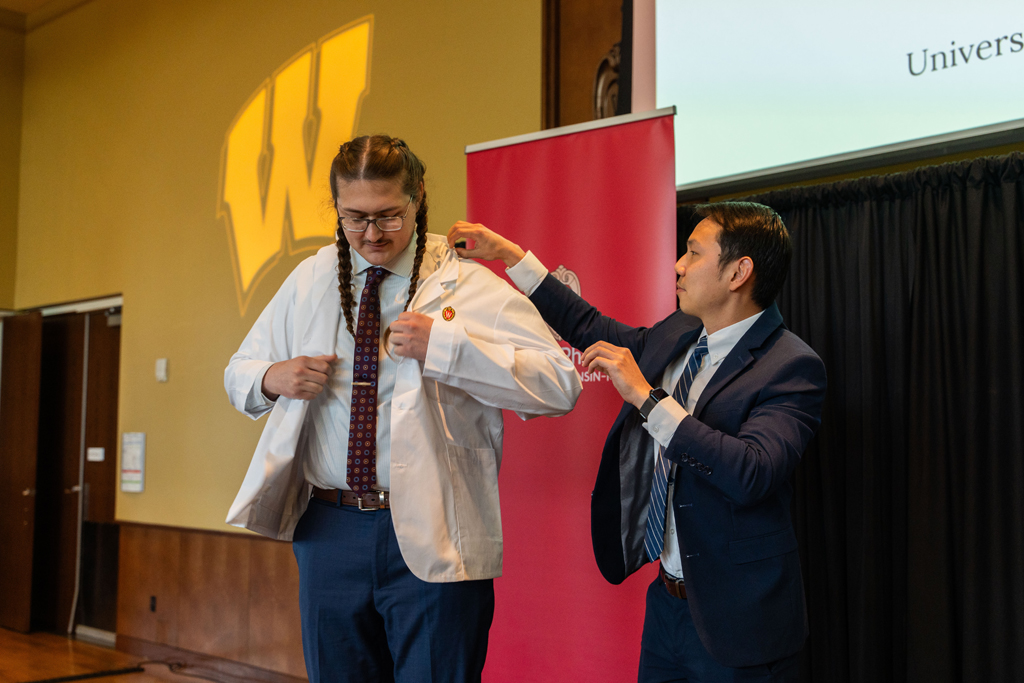 Photo by Paulius Musteikis A student receives his white coat from Sean Lim