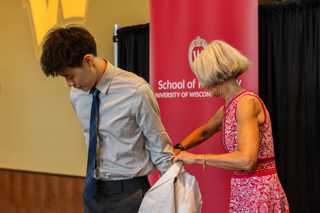 Photo by Paulius Musteikis A student receives his white coat from Mara Kieser