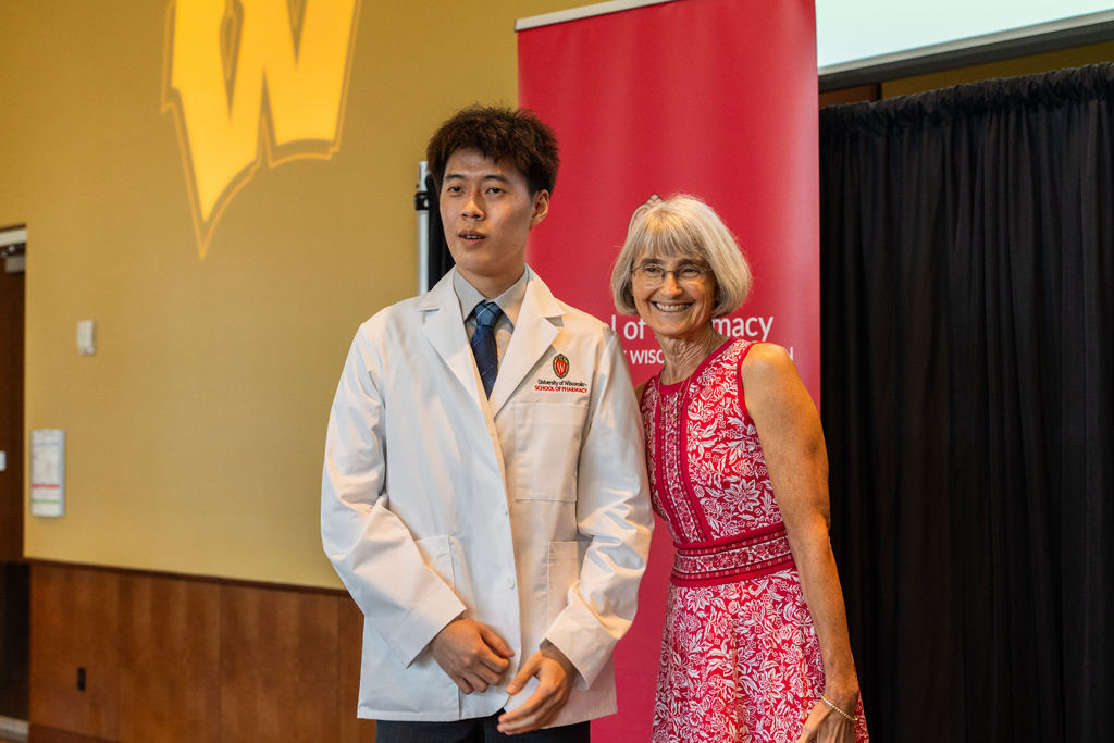 Photo by Paulius Musteikis A student poses with Mara Kieser in front of a red School of Pharmacy banner