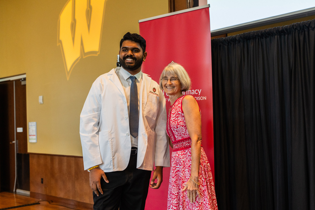 Photo by Paulius Musteikis A student poses with Mara Kieser in front of a red School of Pharmacy banner