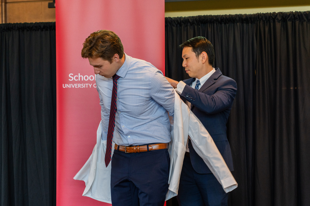 Photo by Paulius Musteikis A student receives his white coat from Sean Lim