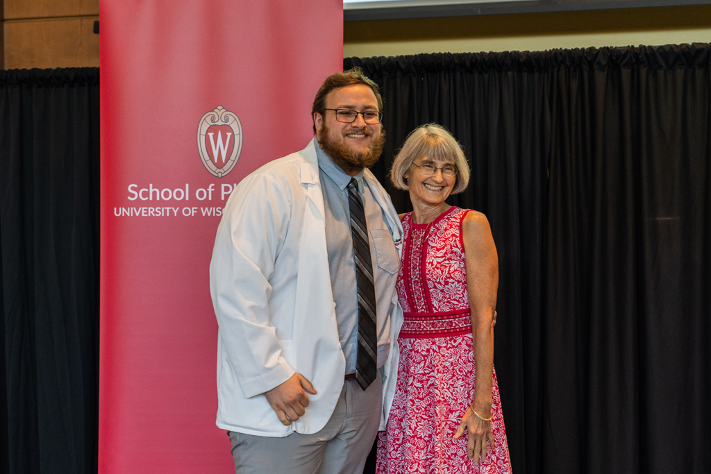 Photo by Paulius Musteikis A student poses with Mara Kieser in front of a red School of Pharmacy banner