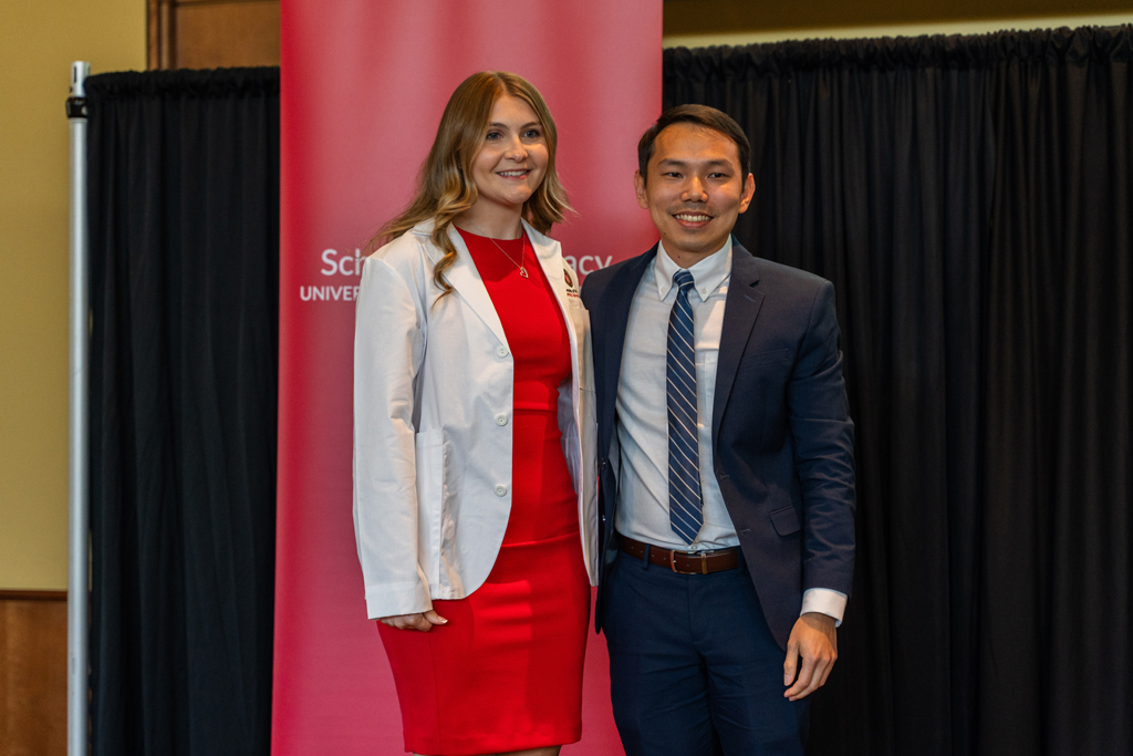 Photo by Paulius Musteikis A student poses with Sean Lim in front of a red School of Pharmacy banner