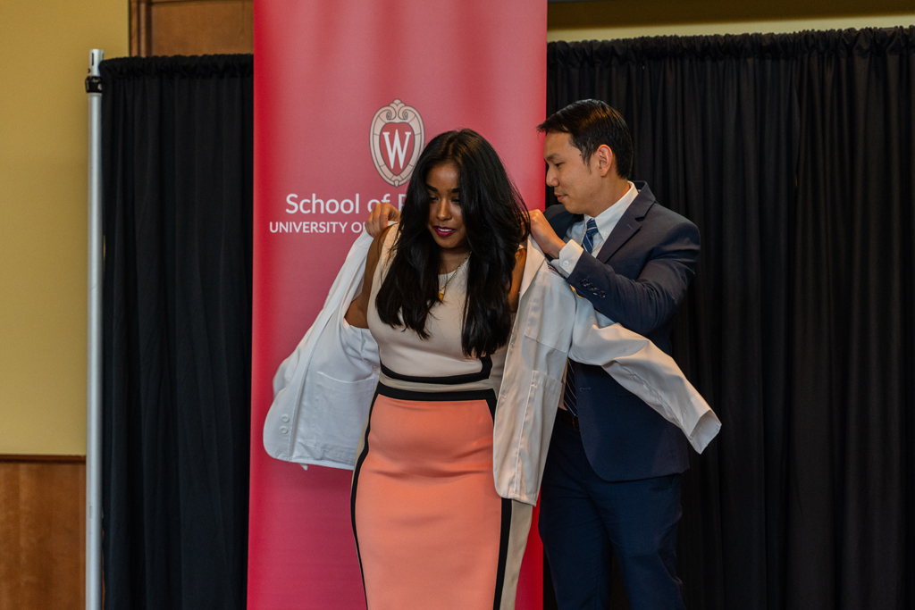 Photo by Paulius Musteikis A student receives her white coat from Sean Lim