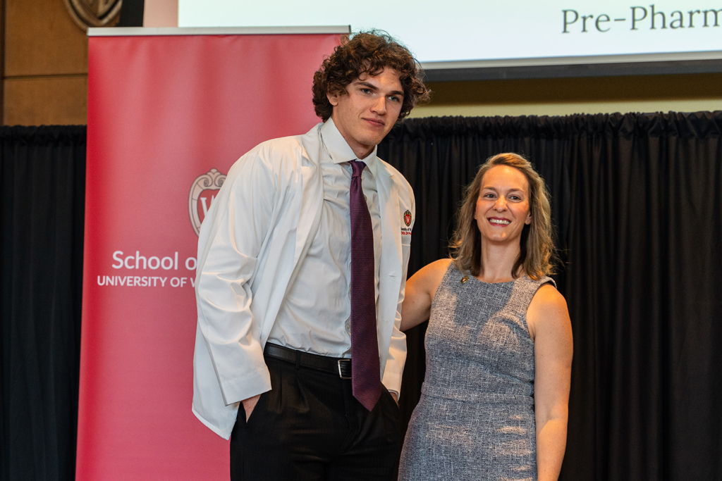 Photo by Paulius Musteikis A student poses with Kate Rotzenberg in front of the red School of Pharmacy banner