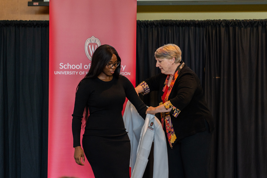 Photo by Paulius Musteikis A student receives her white coat from Karen Kopacek