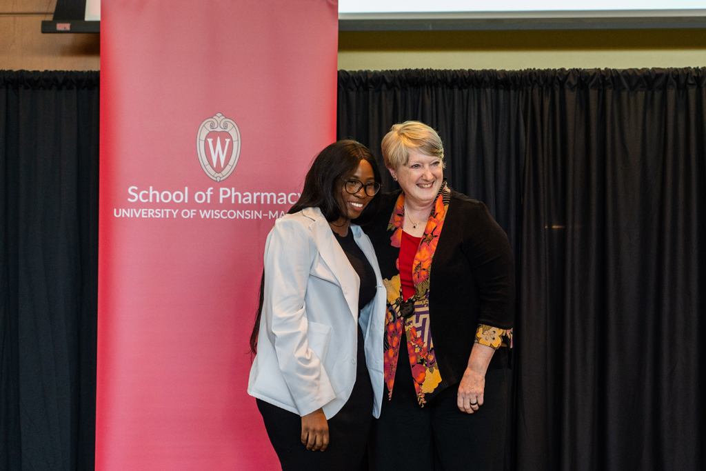 Photo by Paulius Musteikis A student poses with Karen Kopacek in front of the red School of Pharmacy banner