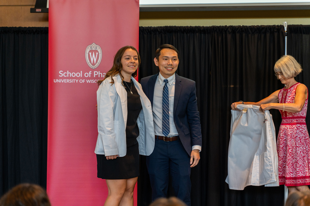 Photo by Paulius Musteikis A student poses with Sean Lim in front of the red School of Pharmacy banner