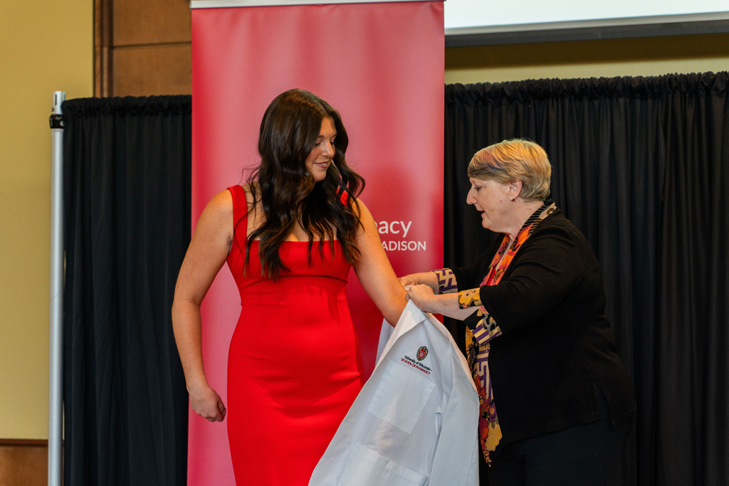 Photo by Paulius Musteikis A student receives her white coat from Karen Kopacek