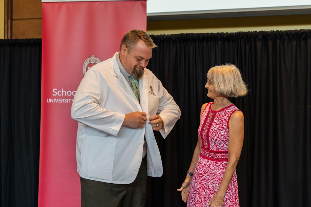 Photo by Paulius Musteikis Mara Kieser watches as a student buttons his white coat