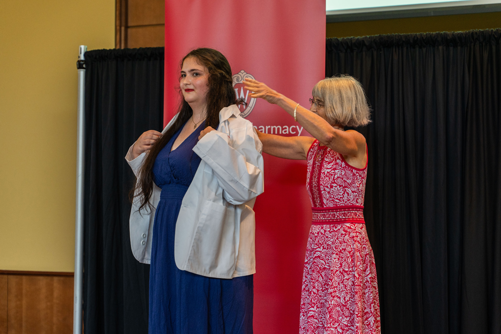 Photo by Paulius Musteikis Mara Kieser places a white coat on a student