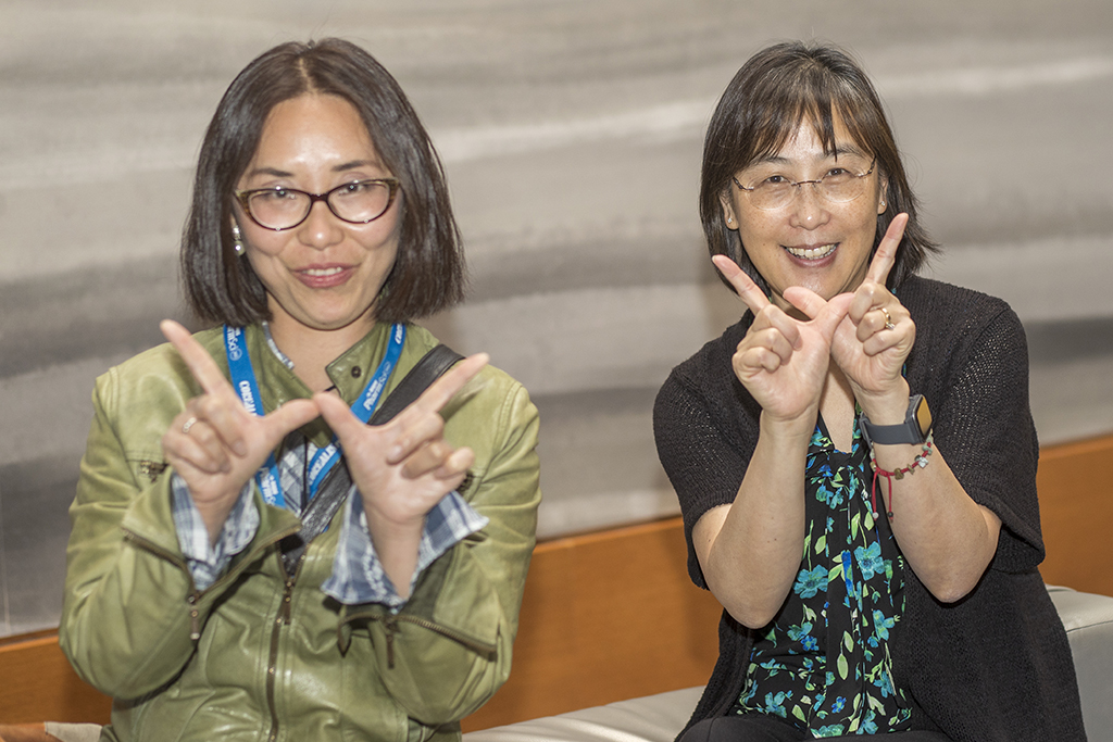 025WU-Boston10-17-22-Osberg Two female attendees holding up "W" hands for Wisconsin.