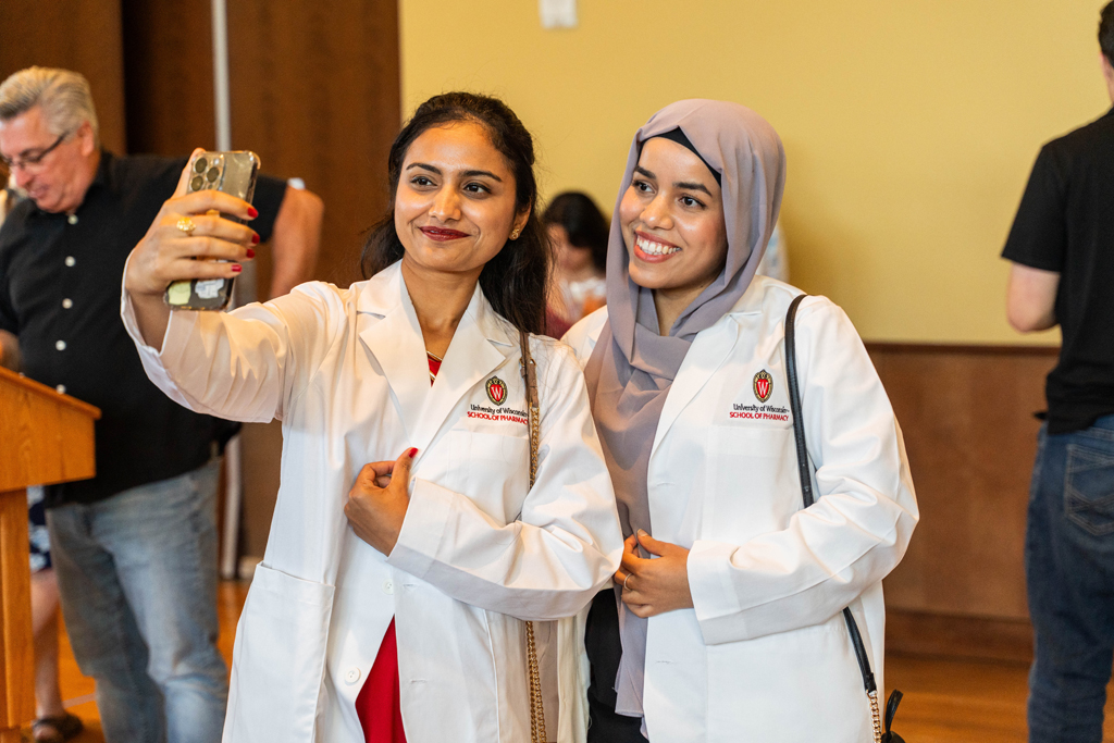 Photo by Paulius Musteikis Two female students in white coats take a smiling selfie