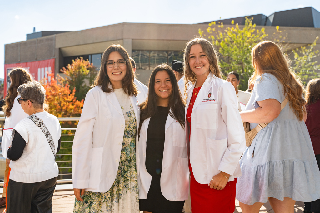 Photo by Paulius Musteikis Three female students pose for a photo outside with people in the background