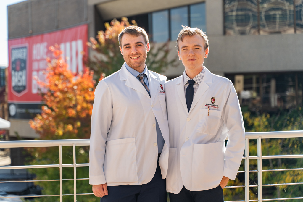 Photo by Paulius Musteikis Two male students in white coats pose outside for a photo