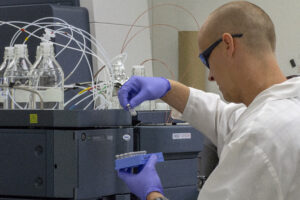 A researcher in a white coat pipetting in a lab.