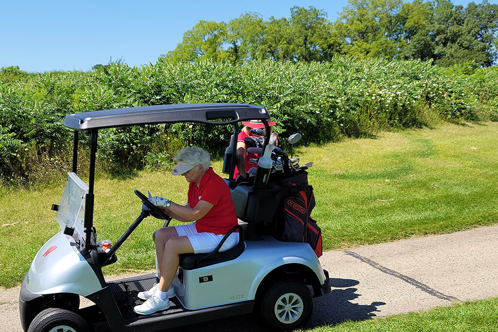 20210813_121556 Female pharm alumni sitting at the wheel in a golf cart