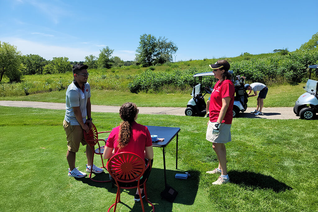 20210813_123754 Event coordinators around table with roll of tickets on it and golf carts stationed on the path behind them