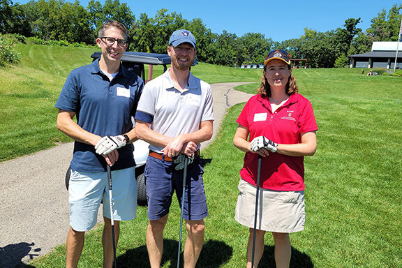 20210813_123851 Pharm alum together in golf apparel holding their clubs