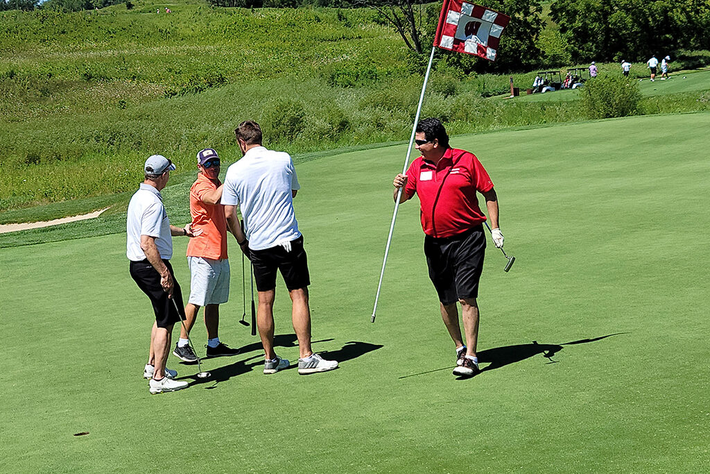 20210813_125436 Pharm Alum carrying golf flagstick with UW logo on it