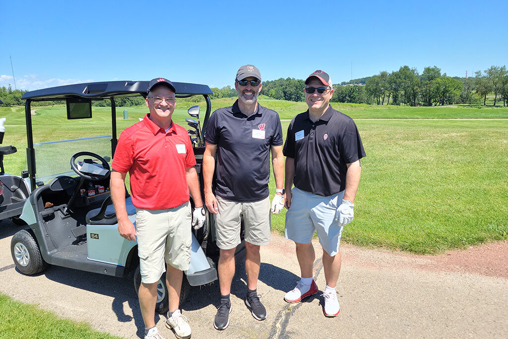 20210813_131038 Dave Mott and other faculty in golf shirts and caps next to a golf cart