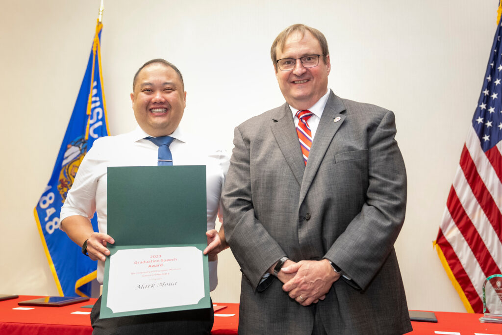 Mark Moua poses with his graduation speech award and Dean Steve Swanson.