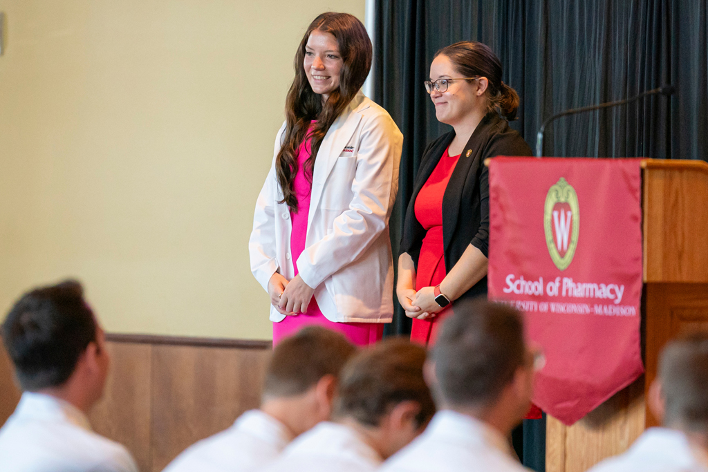 School of Pharmacy White Coat Ceremony Sunday, Sept. 17, 2003. Student in white coat smiling with staff on-stage