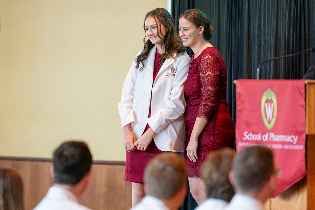 School of Pharmacy White Coat Ceremony Sunday, Sept. 17, 2003. Student in white coat smiling with staff on-stage