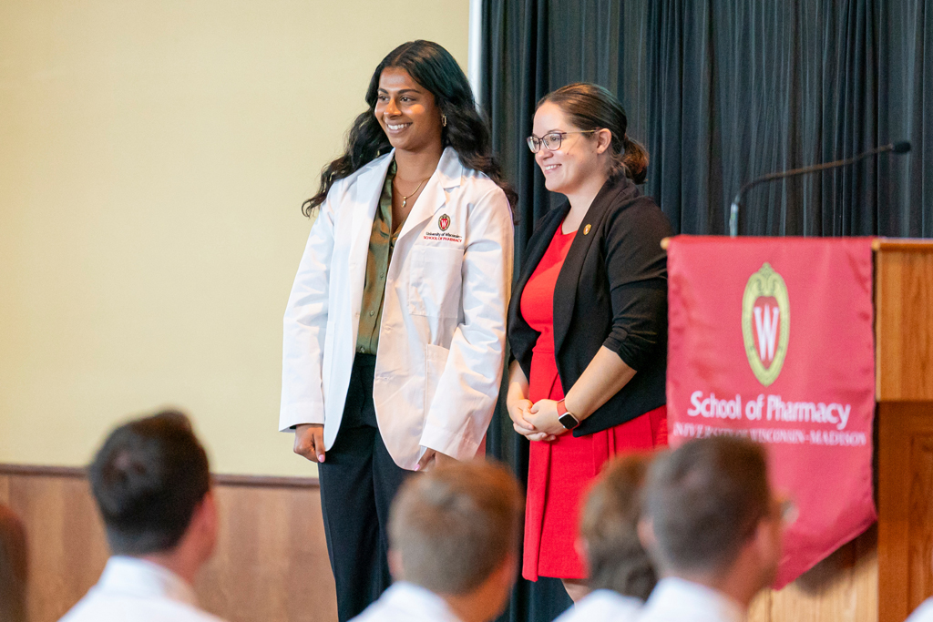 School of Pharmacy White Coat Ceremony Sunday, Sept. 17, 2003. Student in white coat smiling with staff on-stage