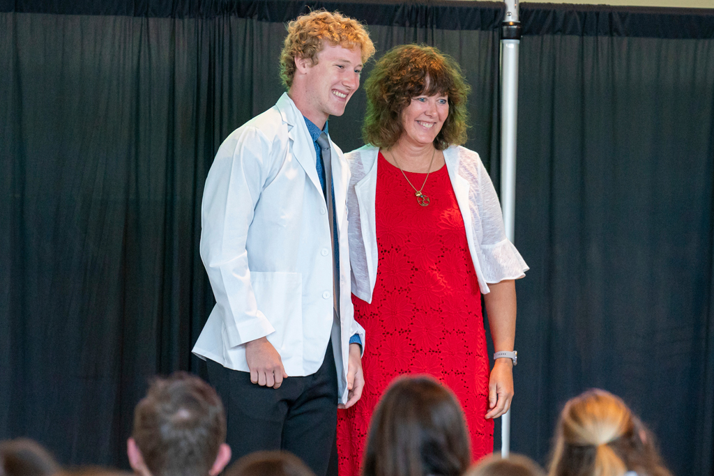 School of Pharmacy White Coat Ceremony Sunday, Sept. 17, 2003. Student in white coat smiling with staff on-stage