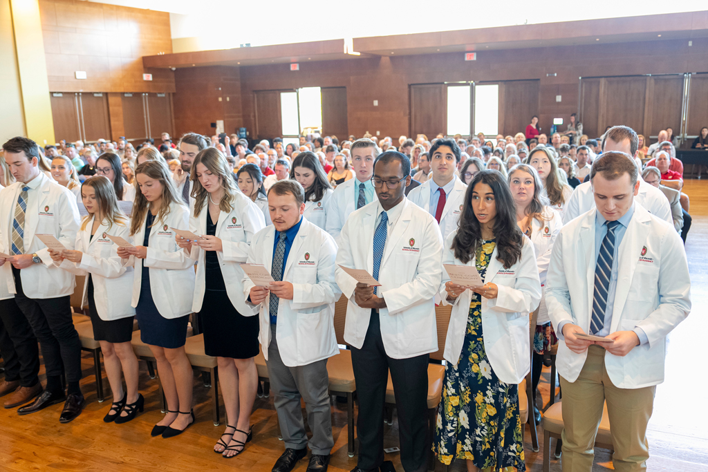 School of Pharmacy White Coat Ceremony Sunday, Sept. 17, 2003. Students in white coats reading off flyer