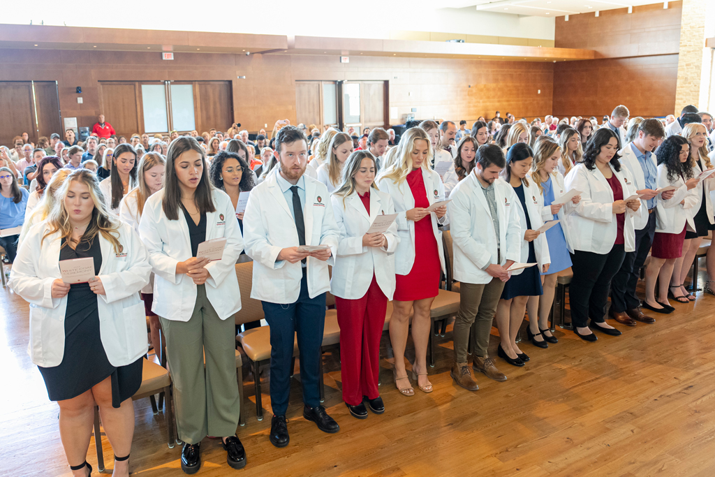 School of Pharmacy White Coat Ceremony Sunday, Sept. 17, 2003. Students in white coats reading their flyers