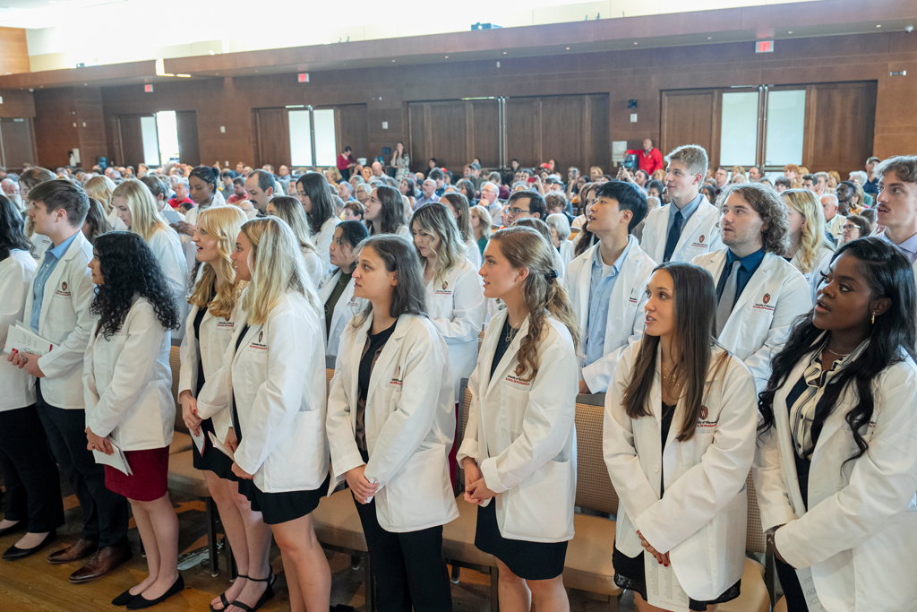 School of Pharmacy White Coat Ceremony Sunday, Sept. 17, 2003. Students in white coats standing from their seats and speaking