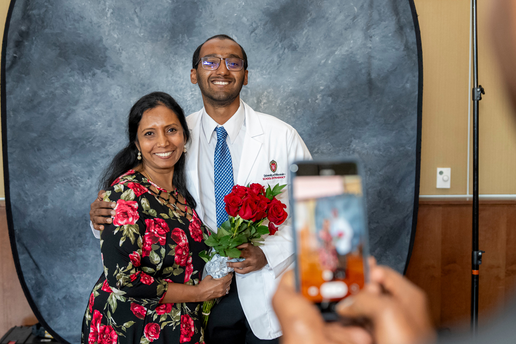 School of Pharmacy White Coat Ceremony Sunday, Sept. 17, 2003. Student smiling and posing together with his mother who has roses in her hand