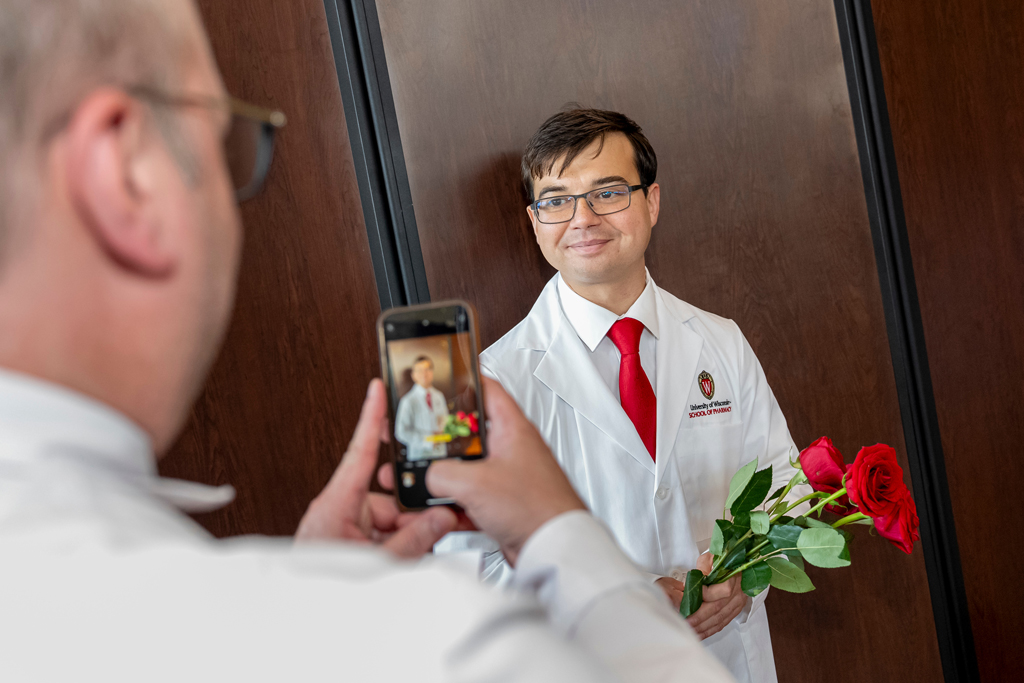 School of Pharmacy White Coat Ceremony Sunday, Sept. 17, 2003. A father taking a photo of his son wearing his white coat and holding roses