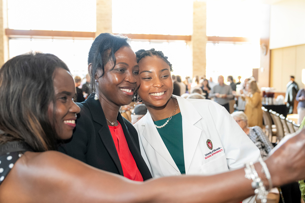 School of Pharmacy White Coat Ceremony Sunday, Sept. 17, 2003. Student in white coat taking a selfie with mother and staff