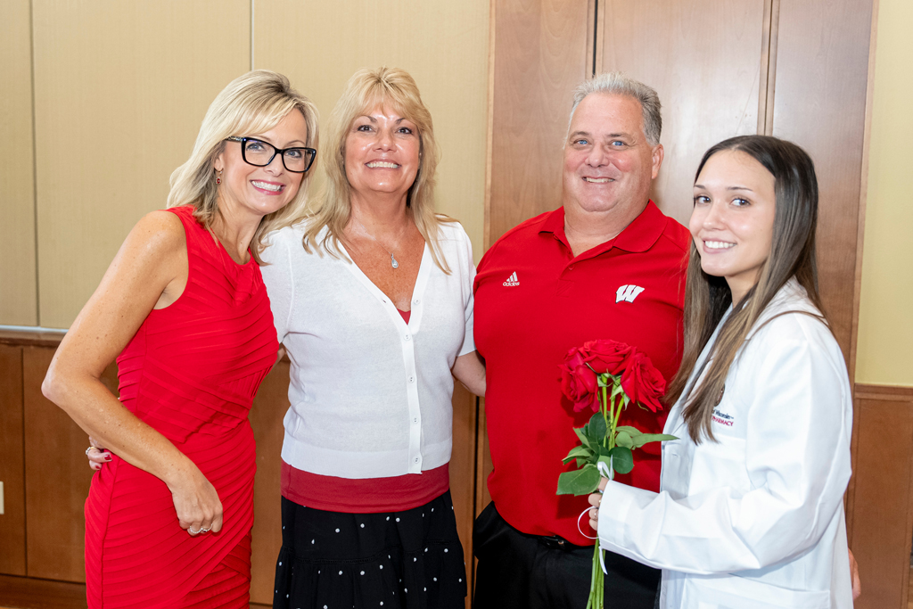 School of Pharmacy White Coat Ceremony Sunday, Sept. 17, 2003. Student in white coat holding flowers together with her parents and Beth Martin