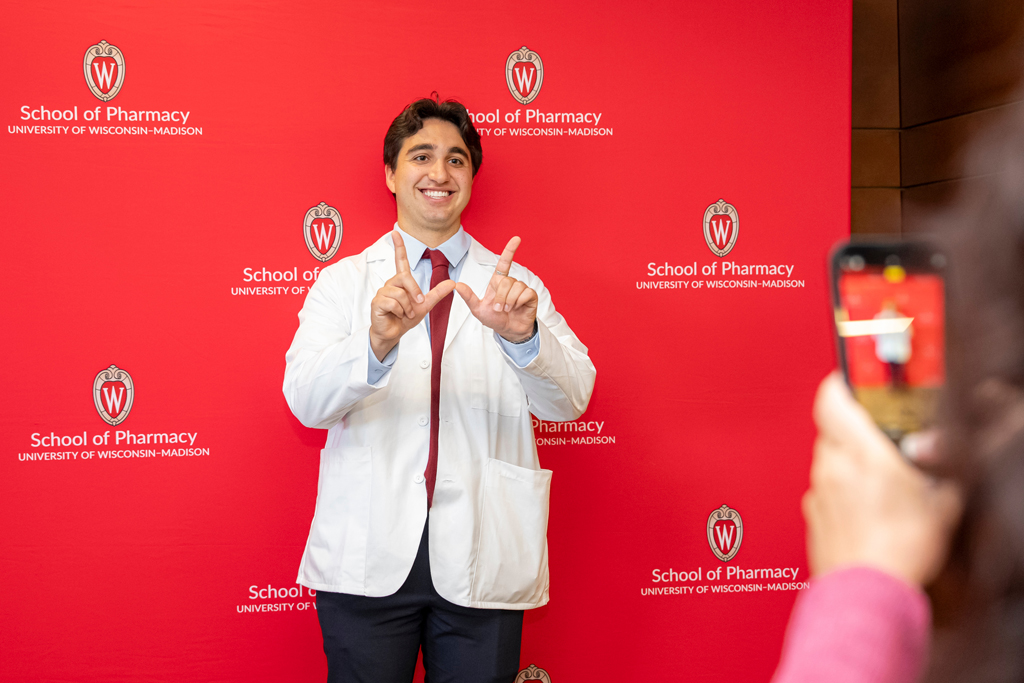 School of Pharmacy White Coat Ceremony Sunday, Sept. 17, 2003. Student in white coat flashing "W" in front of School of Pharmacy background
