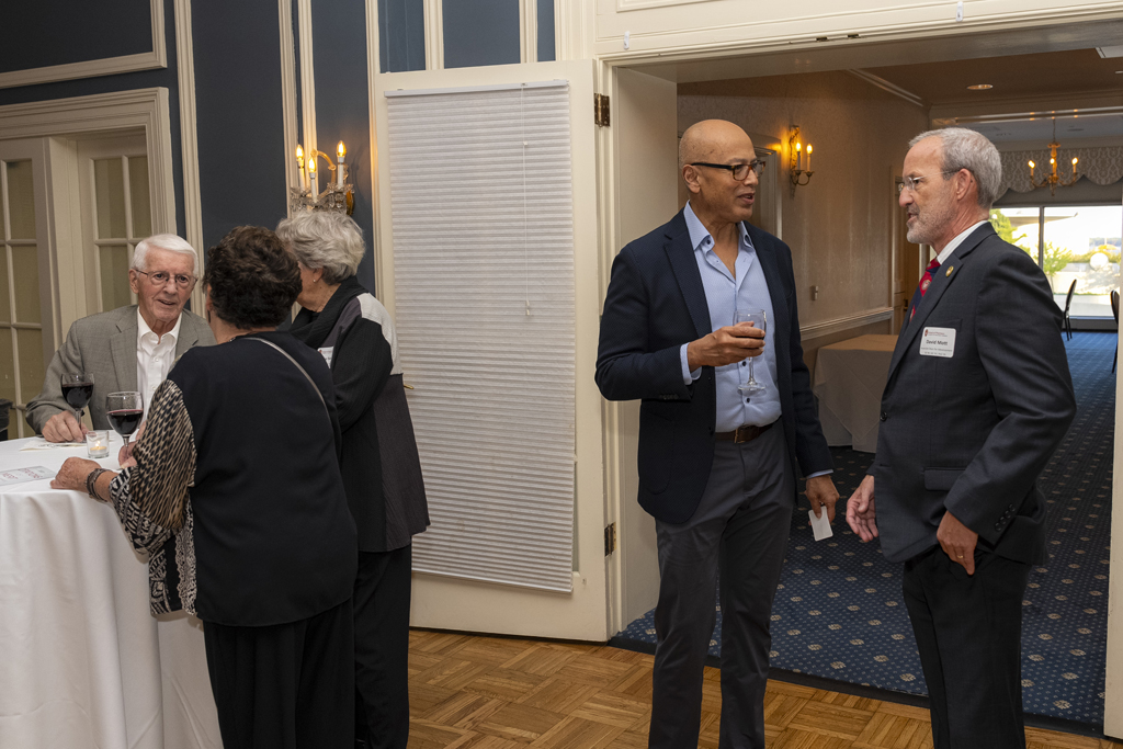 Arash Bashirullah and Dave Mott speak in a doorway, near a table of other visiting attendees