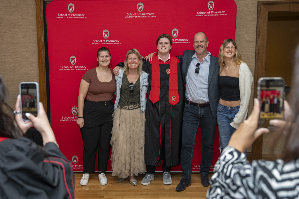 PharmTox Brunch at Carson Gulley May 11, 2024. (Photo © Andy Manis) A PharmTox grad poses with his family in front of a red School of Pharmacy background
