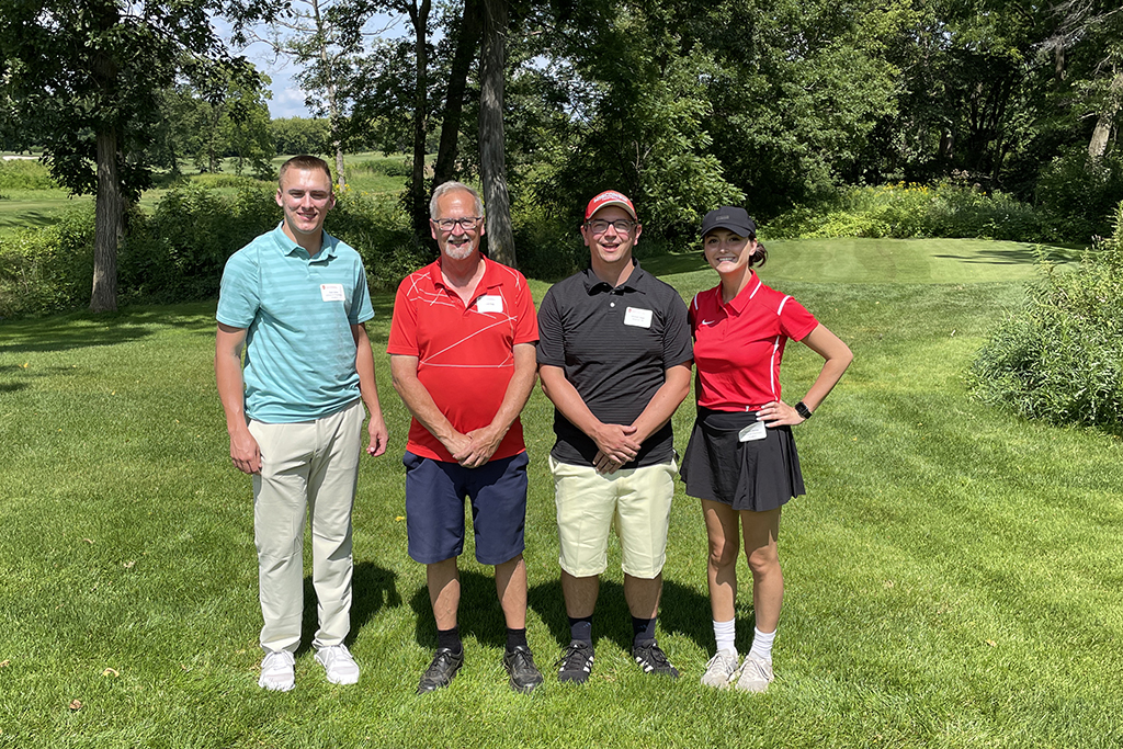 3E1DA2A6-611B-4406-AC4C-36BC17DB3586 A group of alumni smile at the 2022 golf outing, outside in the sun