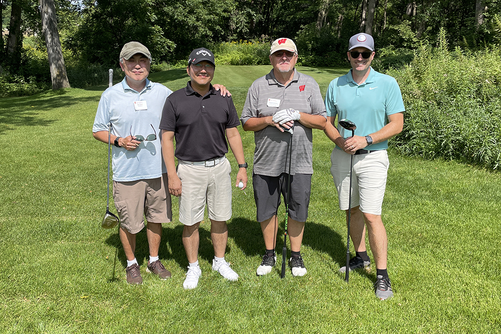 49A73853-14AB-46BC-B5FE-75D9D2F6C0CF A group of alumni smile at the 2022 golf outing, outside in the sun