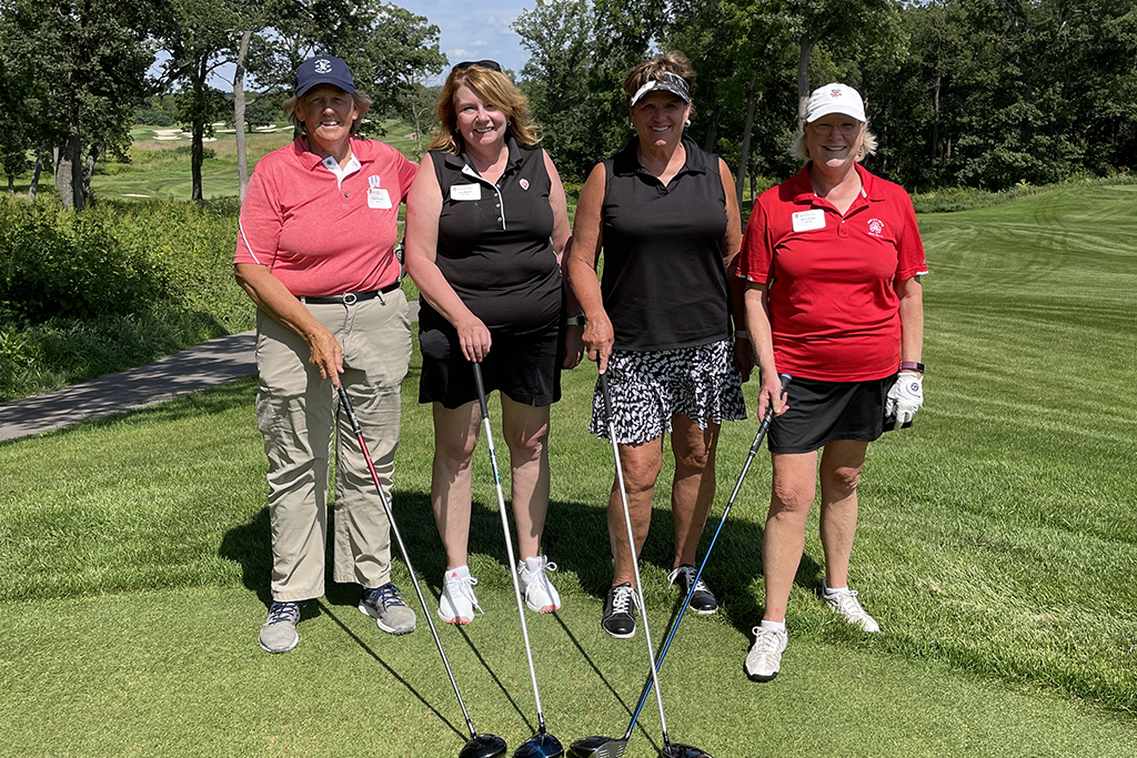8256A3B9-9A8F-463D-8CEB-146909830AED A group of alumni smile at the 2022 golf outing, outside in the sun